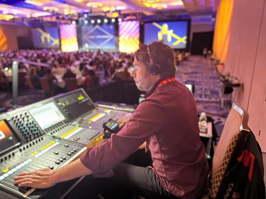 Live event audio technician operating a sound console during a corporate conference event