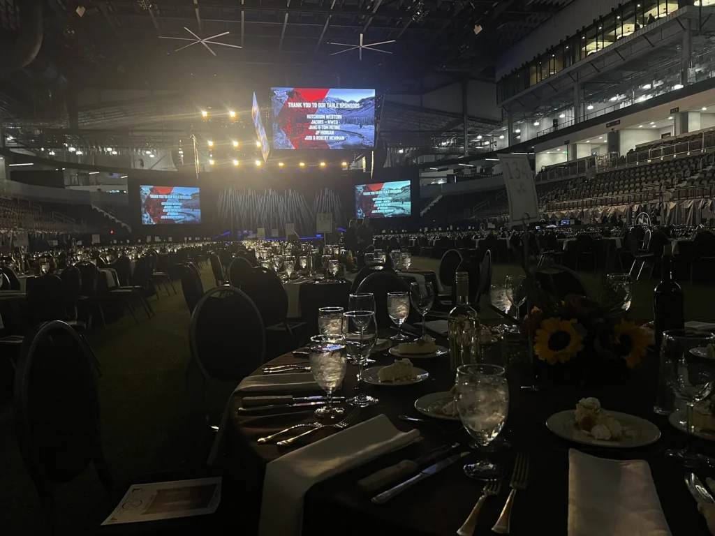 Encompass Event Group sets up a scholarship banquet with dining tables, stage lighting, and sponsor screens.